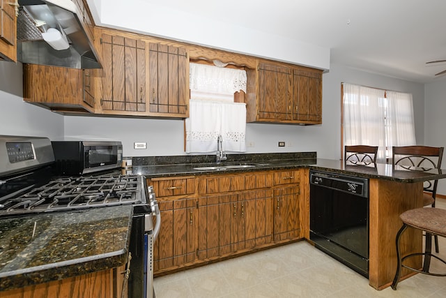 kitchen featuring dark stone counters, stainless steel appliances, sink, a breakfast bar area, and wall chimney range hood