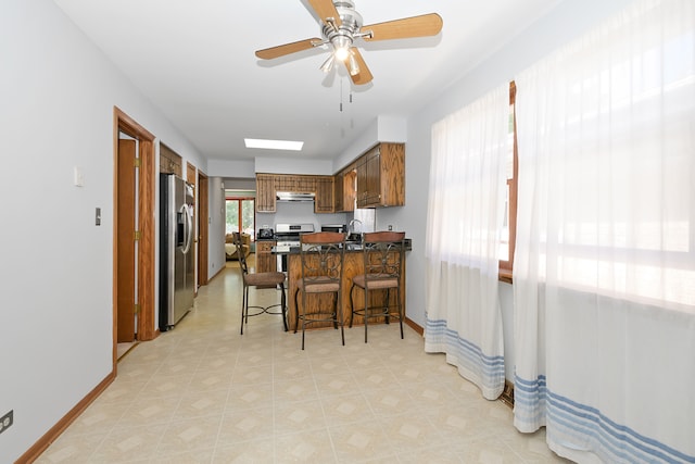 kitchen featuring appliances with stainless steel finishes, a breakfast bar, kitchen peninsula, sink, and ceiling fan