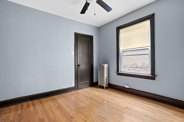 unfurnished room featuring light hardwood / wood-style flooring, ceiling fan, and radiator