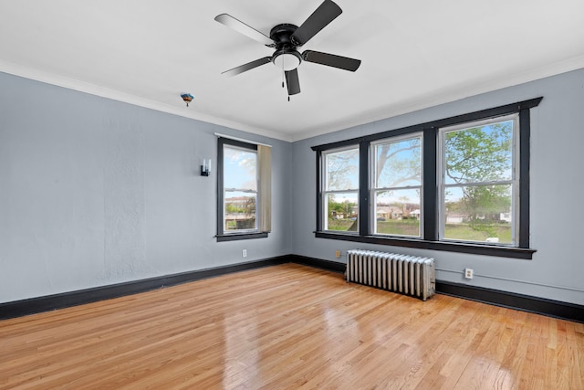 unfurnished room featuring crown molding, radiator, ceiling fan, and light wood-type flooring