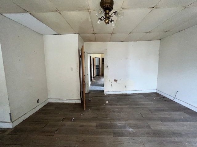 unfurnished room with dark wood-type flooring and a drop ceiling