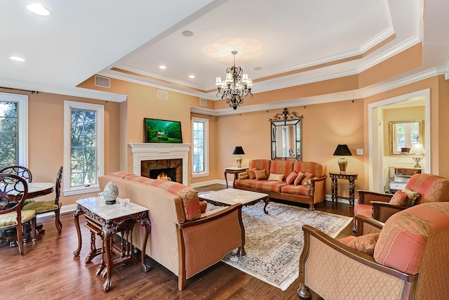 living room featuring crown molding, a notable chandelier, a raised ceiling, and dark hardwood / wood-style floors