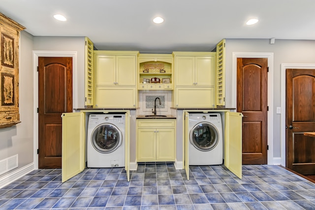 washroom featuring dark tile flooring, washer / clothes dryer, cabinets, and sink