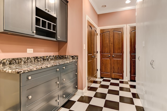 kitchen with crown molding, dark tile floors, dark stone countertops, and gray cabinets