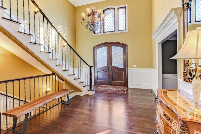 entrance foyer featuring a chandelier, a towering ceiling, dark hardwood / wood-style floors, and french doors