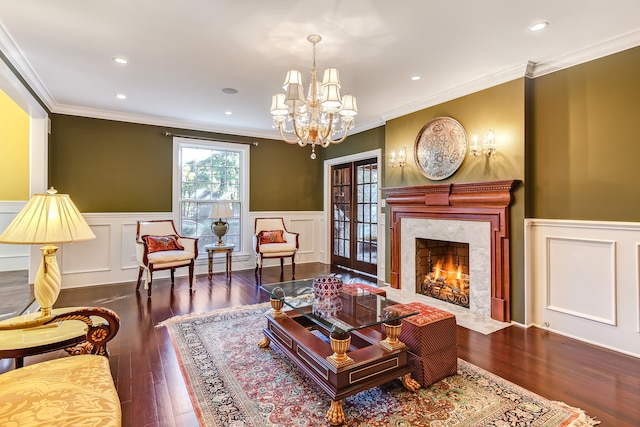 living room featuring a chandelier, a fireplace, french doors, dark wood-type flooring, and crown molding