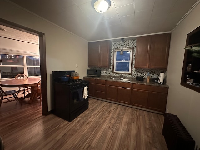 kitchen with black gas stove, radiator heating unit, dark hardwood / wood-style floors, and sink