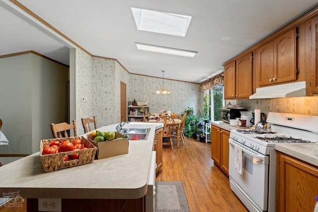 kitchen with a chandelier, a skylight, hanging light fixtures, white range with gas cooktop, and sink