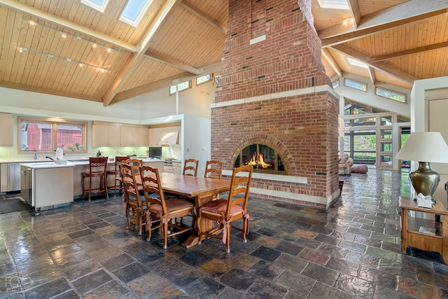 tiled dining area with a skylight, track lighting, a fireplace, and high vaulted ceiling