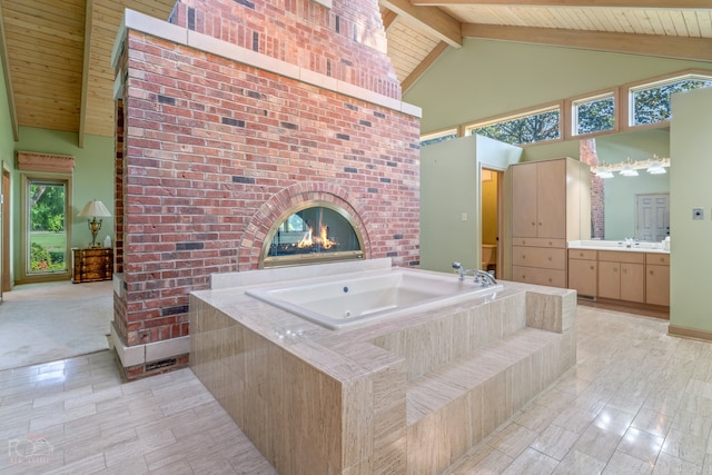 bathroom with beamed ceiling, a brick fireplace, vanity, high vaulted ceiling, and a bathtub