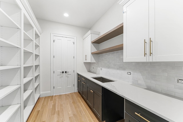 interior space with white cabinets, light wood-type flooring, tasteful backsplash, and light stone countertops