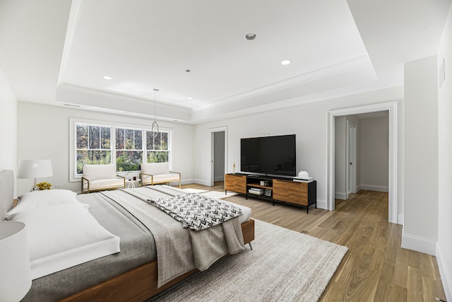 bedroom featuring light hardwood / wood-style flooring and a tray ceiling