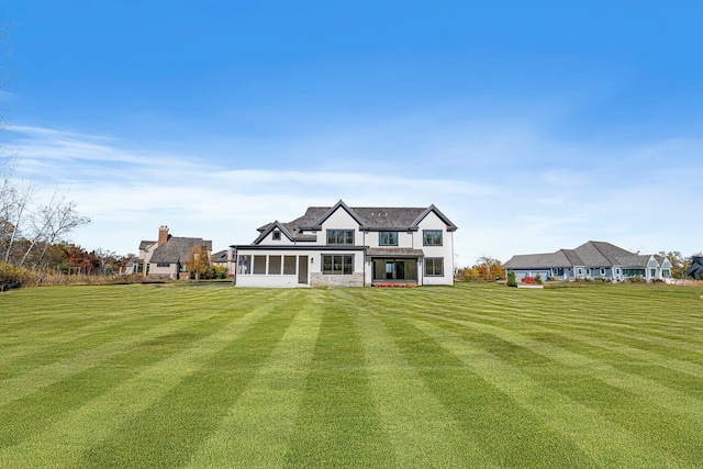 back of house featuring a lawn and a sunroom