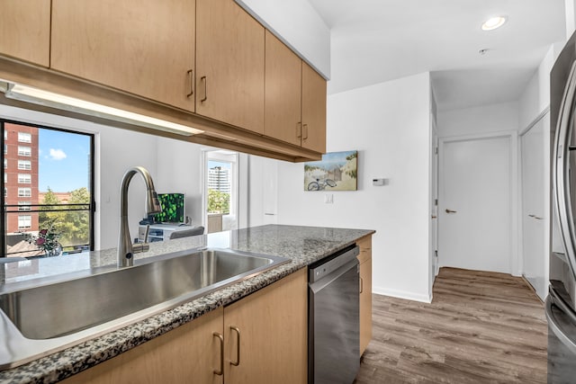 kitchen featuring light brown cabinets, light hardwood / wood-style floors, dark stone counters, appliances with stainless steel finishes, and sink