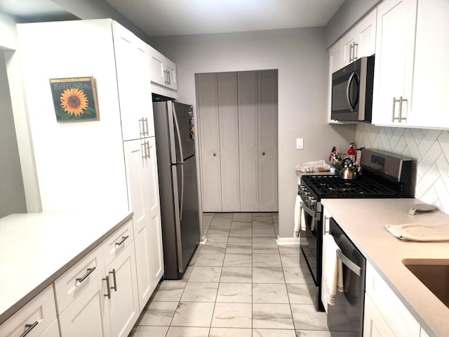 kitchen with appliances with stainless steel finishes, tasteful backsplash, light countertops, marble finish floor, and white cabinetry