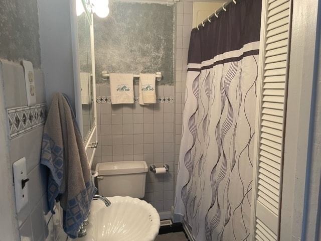 bathroom with tile walls, toilet, and sink