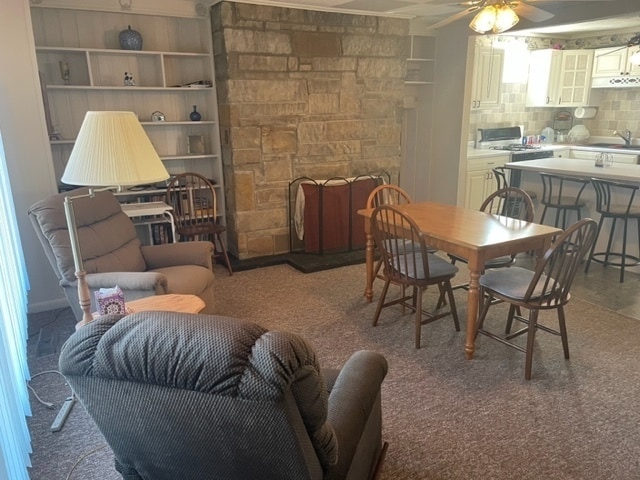 carpeted dining area featuring ceiling fan, sink, and a fireplace