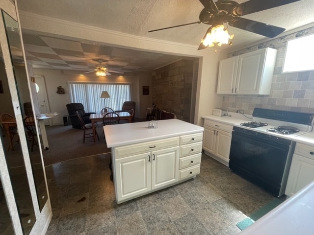 kitchen featuring ceiling fan, light tile floors, white range with gas cooktop, backsplash, and a textured ceiling