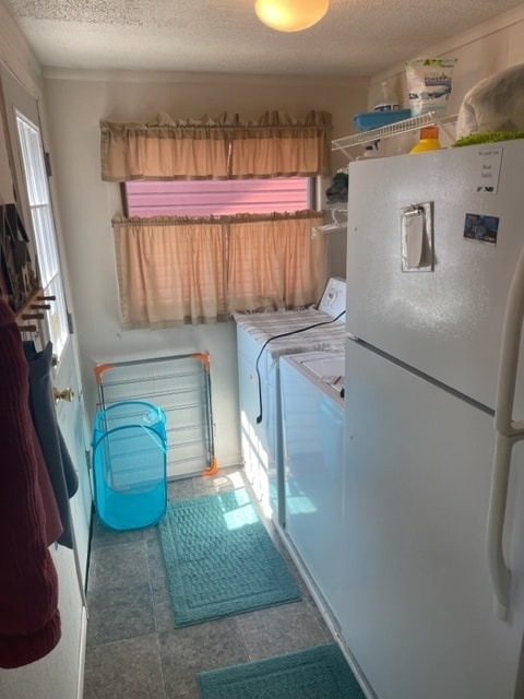 laundry room with washing machine and dryer, a textured ceiling, and dark tile flooring