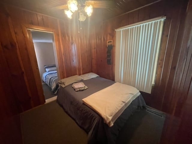 bedroom with ceiling fan and wooden walls