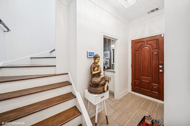 entryway with a chandelier and crown molding