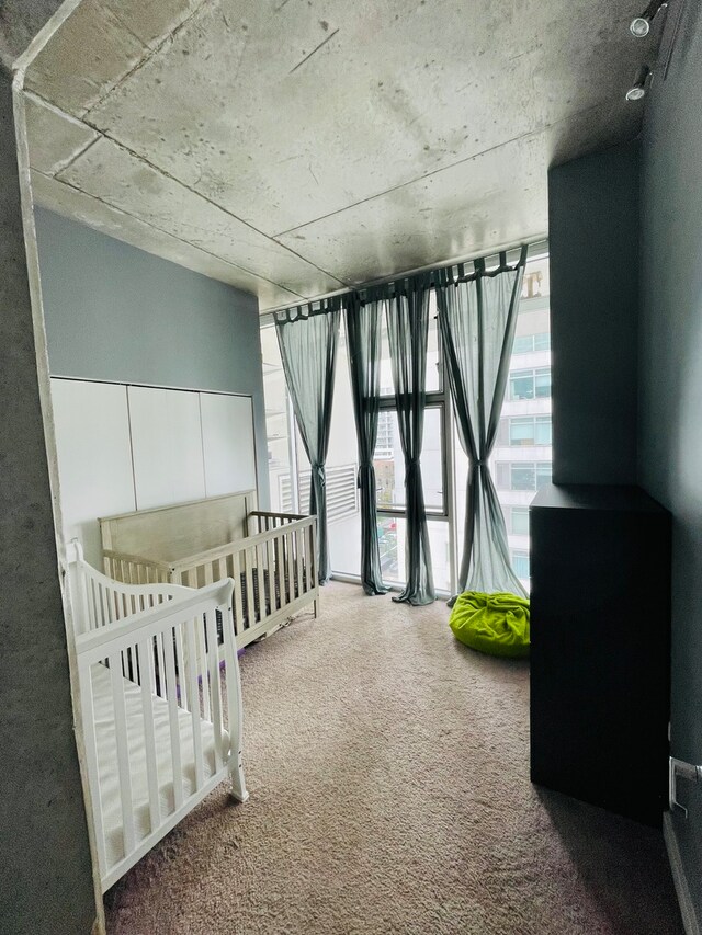 unfurnished bedroom featuring floor to ceiling windows, carpet floors, and a nursery area