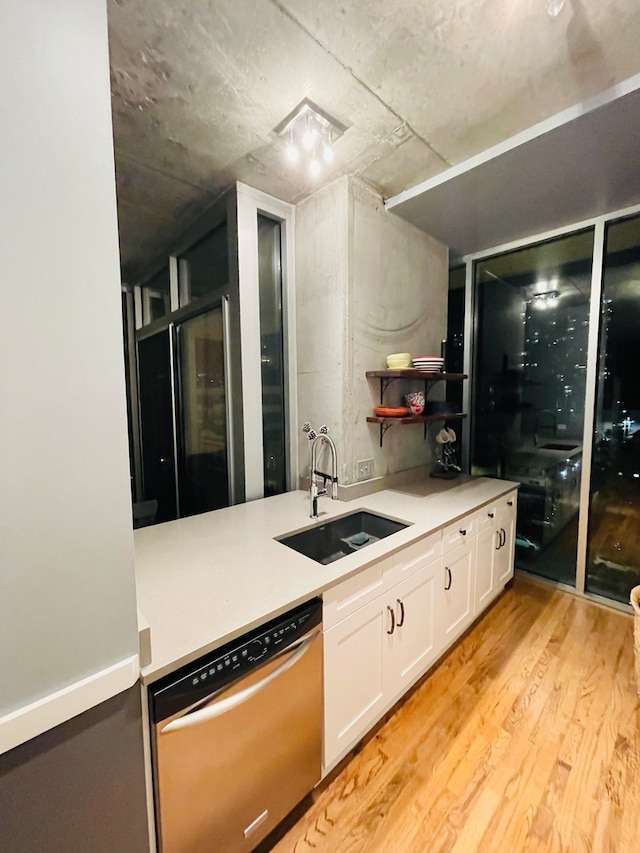 kitchen with light wood-type flooring, stainless steel dishwasher, white cabinetry, and sink