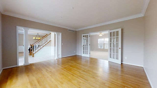 spare room featuring french doors, light hardwood / wood-style floors, ceiling fan with notable chandelier, and decorative columns