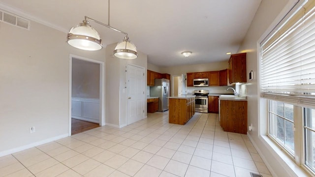 kitchen with appliances with stainless steel finishes, pendant lighting, a kitchen island, and light tile floors