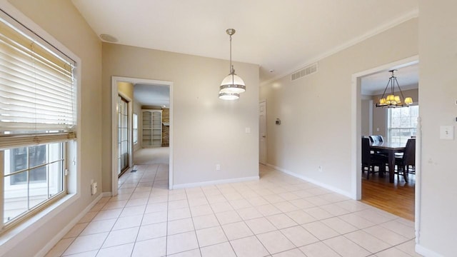 empty room featuring a notable chandelier, ornamental molding, and light tile floors