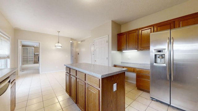 kitchen with light tile flooring, stainless steel fridge with ice dispenser, decorative light fixtures, and a kitchen island