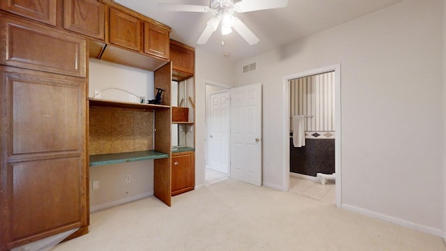 office space with ceiling fan, built in desk, and light colored carpet