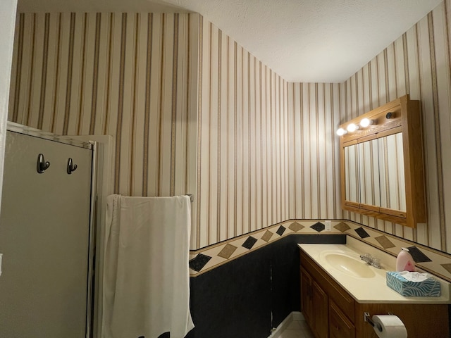 bathroom with a shower with door, a textured ceiling, and vanity