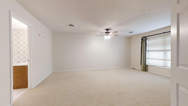 carpeted spare room featuring a textured ceiling and ceiling fan