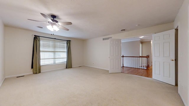 empty room featuring ceiling fan and light colored carpet