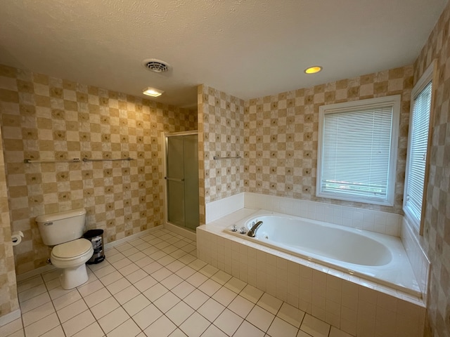 bathroom with tile floors, plus walk in shower, toilet, and a textured ceiling