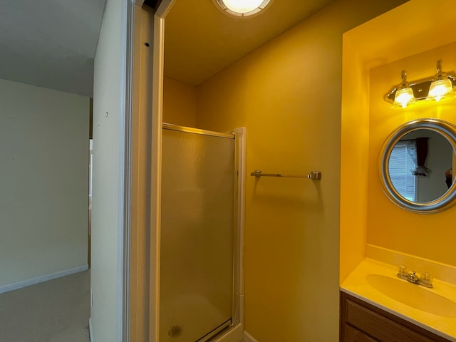 bathroom featuring a shower with door and vanity