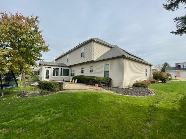 rear view of property with a patio, a trampoline, and a yard