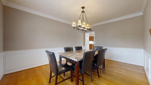 dining space featuring ornamental molding, light wood-type flooring, and an inviting chandelier