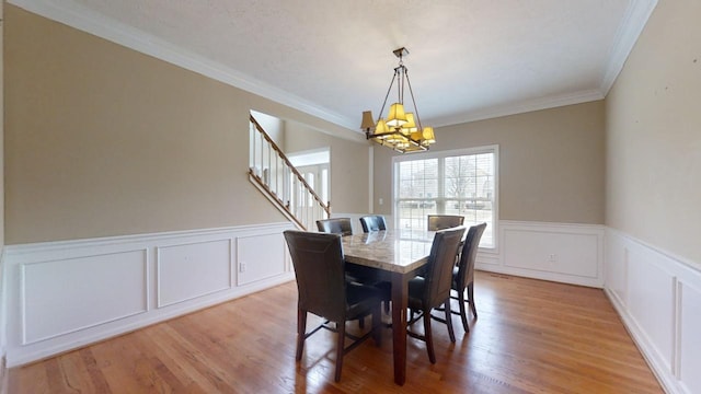 dining space with a chandelier, ornamental molding, and light hardwood / wood-style flooring