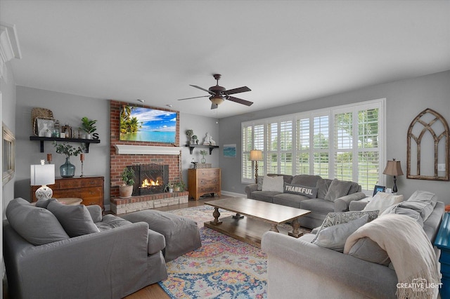 5085 Half Round Rd, Oswego, IL 60543 - living room featuring a brick fireplace, a ceiling fan, wood finished floors, and baseboards