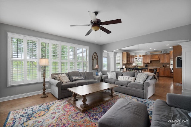 5085 Half Round Rd, Oswego, IL 60543 - living room featuring ornate columns, ceiling fan, wood finished floors, baseboards, and arched walkways