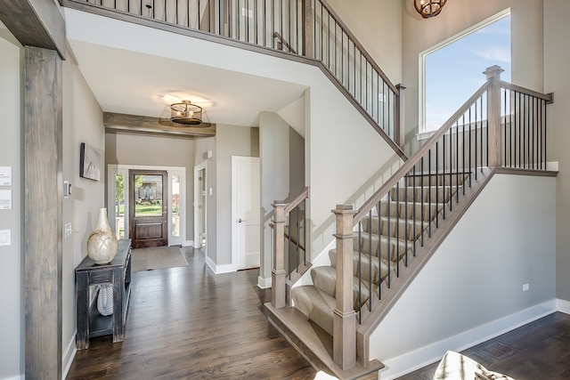 foyer entrance with dark wood-type flooring and a towering ceiling