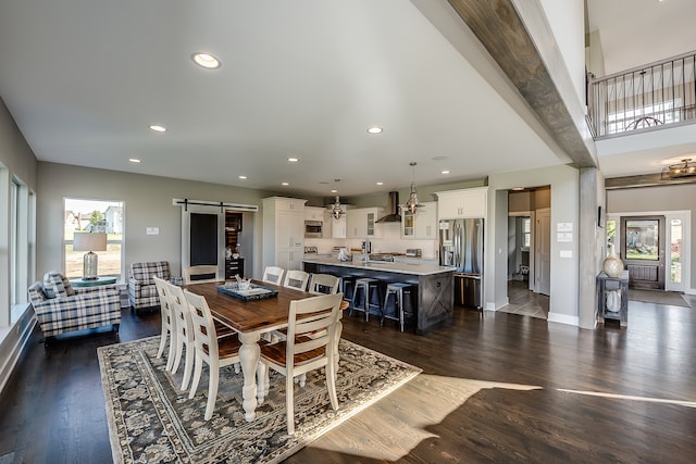 tiled dining space featuring a barn door, a high ceiling, sink, and an inviting chandelier