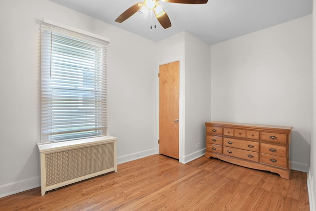 bedroom with radiator heating unit, ceiling fan, and light hardwood / wood-style flooring