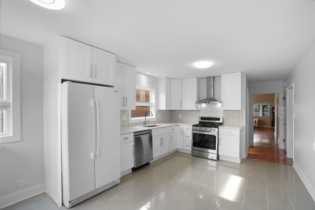 kitchen featuring white cabinets, appliances with stainless steel finishes, light tile flooring, and wall chimney range hood