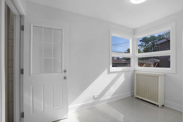 empty room featuring light tile floors, a wealth of natural light, and radiator