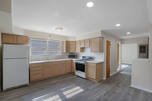 kitchen featuring light brown cabinets, light hardwood / wood-style flooring, backsplash, white appliances, and sink