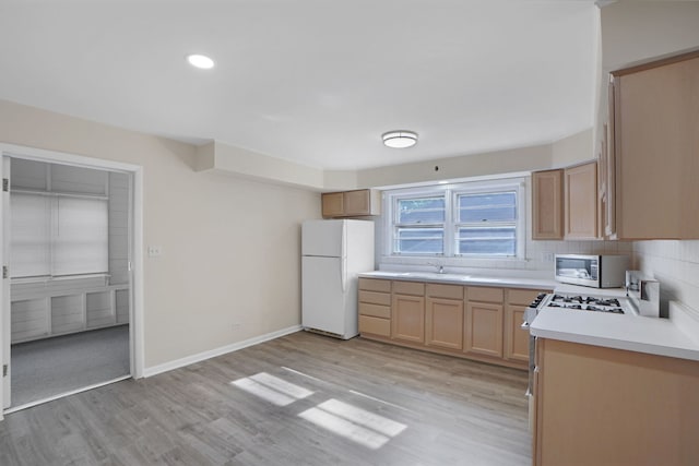 kitchen featuring tasteful backsplash, light brown cabinets, white fridge, and light hardwood / wood-style flooring