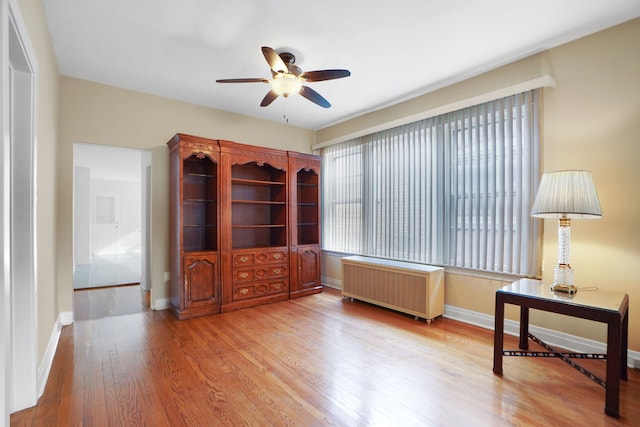 living area featuring radiator heating unit, ceiling fan, and light hardwood / wood-style floors